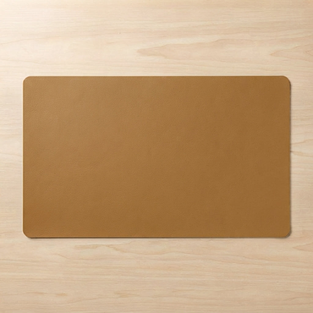 A rectangular tan desk mat with rounded corners, displayed flat on a light wood grain surface.