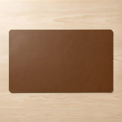A rectangular brown leather desk mat with rounded corners, displayed flat on a light wood grain surface.