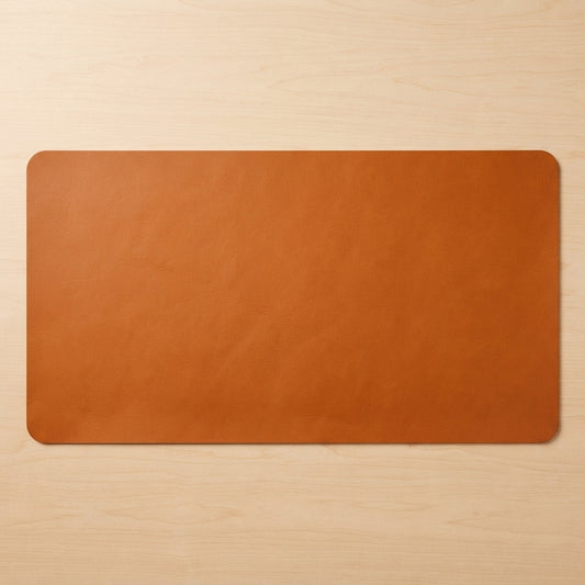 A rectangular tan leather desk mat with rounded corners, displayed flat on a light wood grain surface.