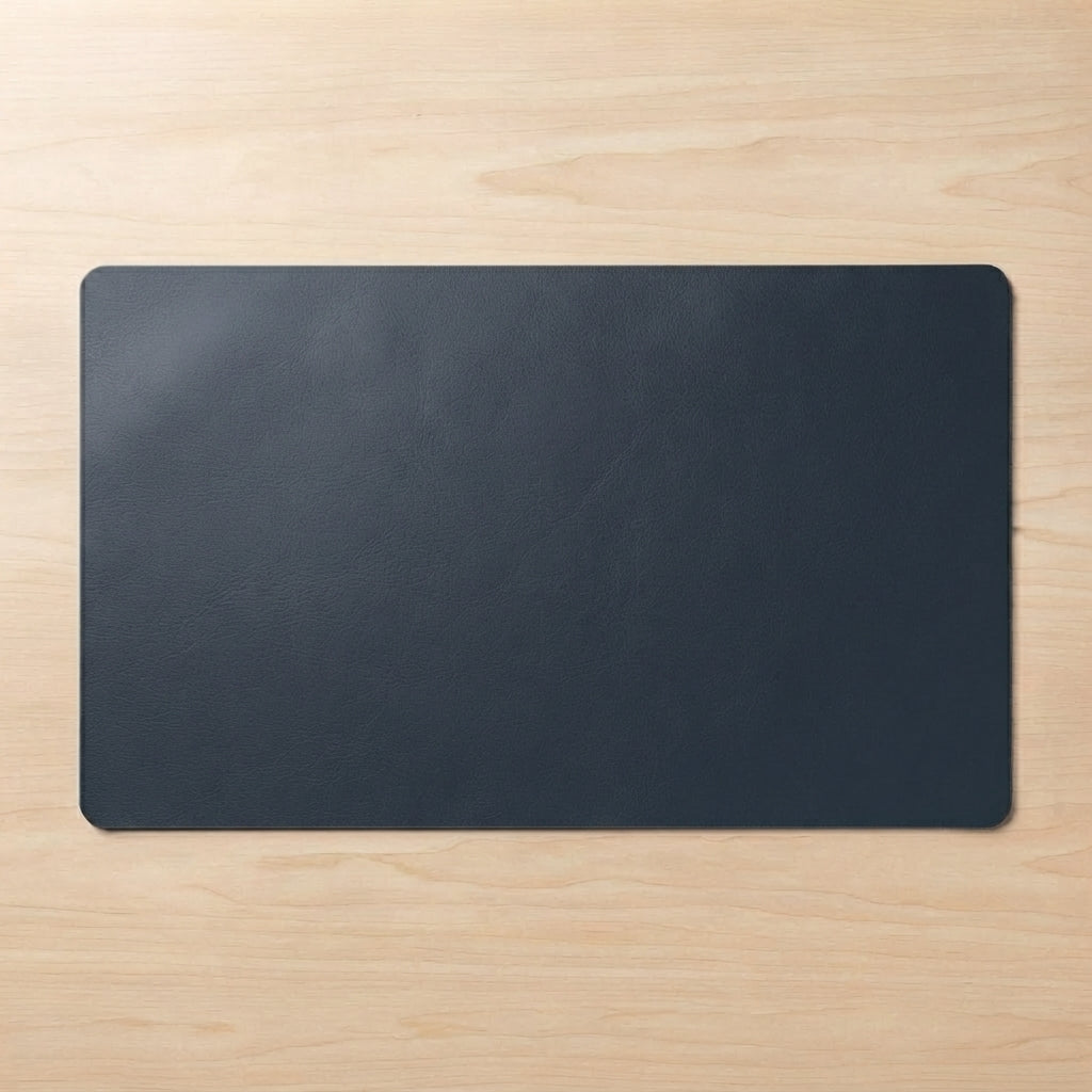 A dark charcoal gray rectangular desk mat with rounded corners, laid flat on a light wood grain surface.